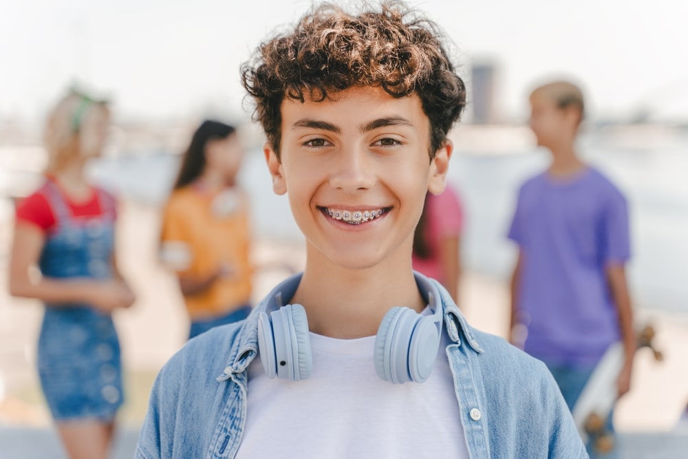 smiling teenage boy with braces wearing headphones