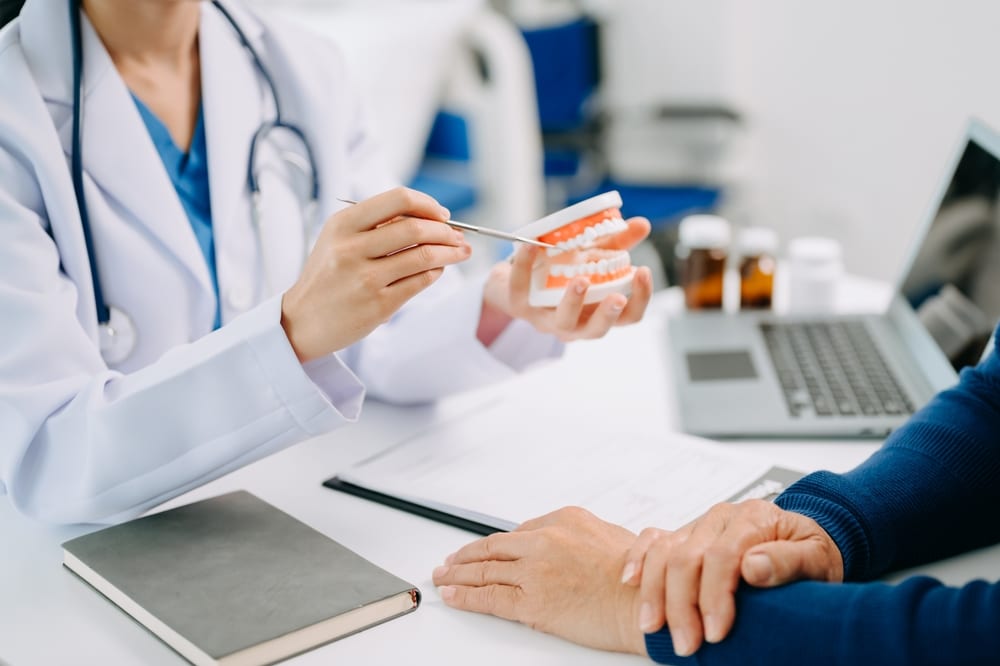 dentist sitting at table with tooth model